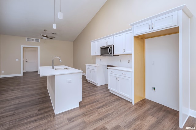 kitchen with ceiling fan, sink, hanging light fixtures, a center island with sink, and white cabinets