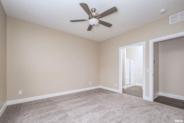 unfurnished bedroom featuring dark colored carpet, a textured ceiling, and ceiling fan