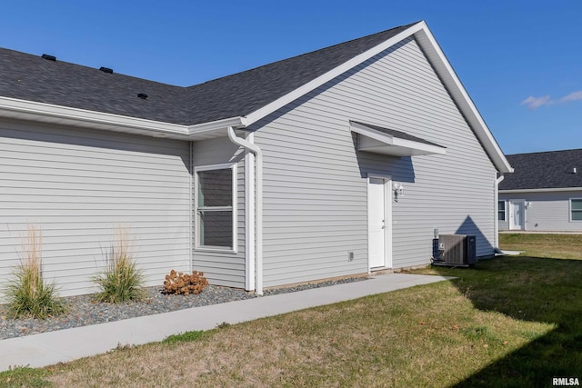 view of side of home featuring central AC unit and a yard