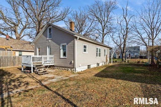 rear view of house featuring a lawn and a deck