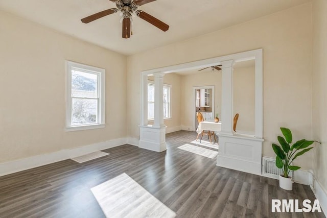 unfurnished room featuring decorative columns, ceiling fan, and dark hardwood / wood-style floors