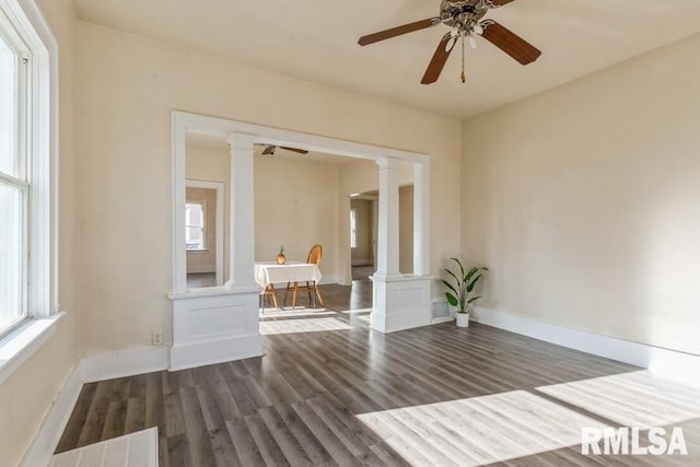 unfurnished room featuring a healthy amount of sunlight, dark hardwood / wood-style flooring, and decorative columns