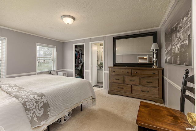 carpeted bedroom featuring a textured ceiling, connected bathroom, a spacious closet, and a closet