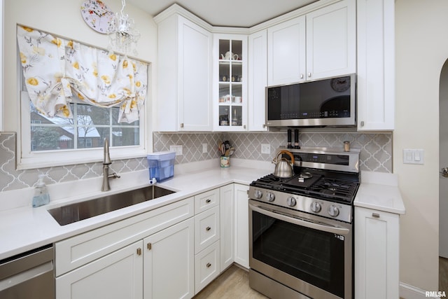 kitchen with white cabinets, appliances with stainless steel finishes, tasteful backsplash, and sink