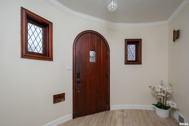 entryway with a chandelier, light wood-type flooring, and crown molding