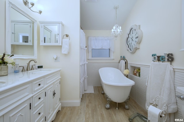 bathroom with a tub, an inviting chandelier, hardwood / wood-style floors, lofted ceiling, and vanity