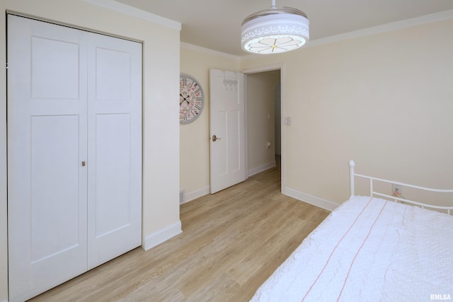 bedroom featuring light wood-type flooring, ornamental molding, and a closet