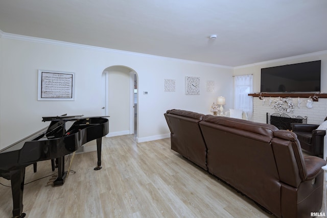 living room featuring crown molding, light hardwood / wood-style floors, and a brick fireplace