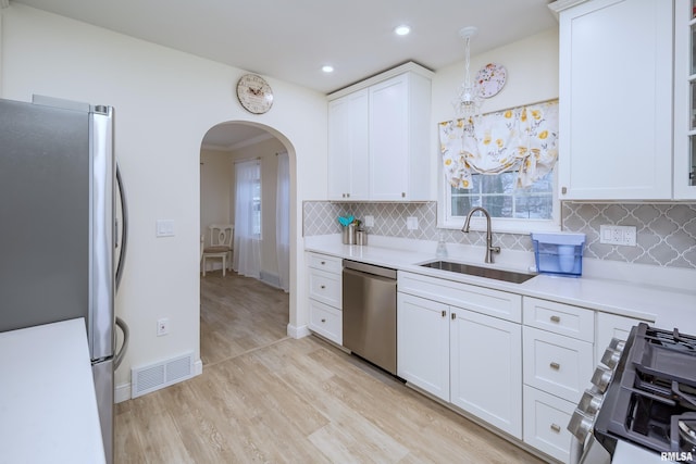 kitchen featuring light wood-type flooring, tasteful backsplash, stainless steel appliances, sink, and white cabinetry