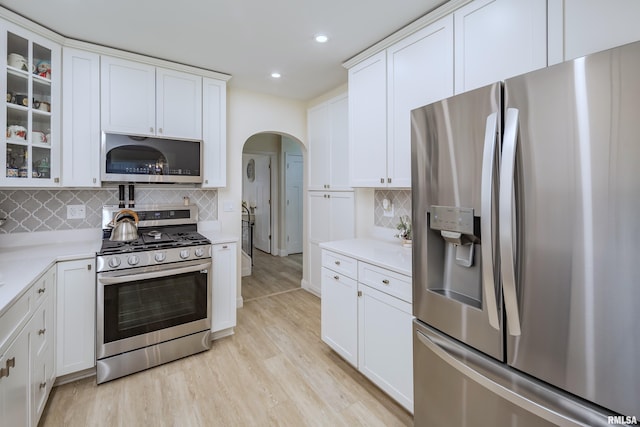 kitchen featuring tasteful backsplash, white cabinetry, stainless steel appliances, and light hardwood / wood-style floors