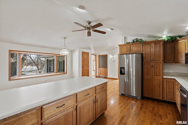 kitchen featuring dark wood-type flooring, vaulted ceiling, ceiling fan, appliances with stainless steel finishes, and decorative light fixtures