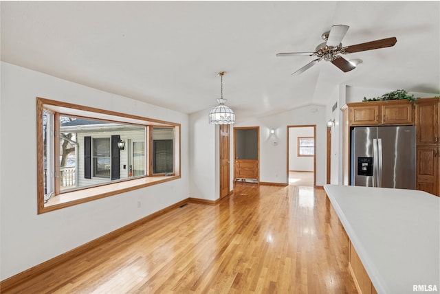 kitchen featuring stainless steel fridge with ice dispenser, hanging light fixtures, vaulted ceiling, and light wood-type flooring