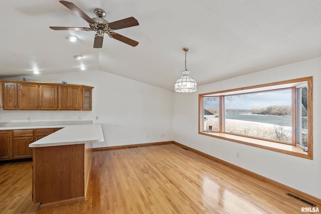 kitchen featuring lofted ceiling, hanging light fixtures, light hardwood / wood-style flooring, ceiling fan, and kitchen peninsula