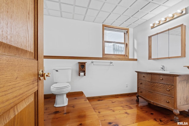 bathroom featuring wood-type flooring, vanity, toilet, and a paneled ceiling