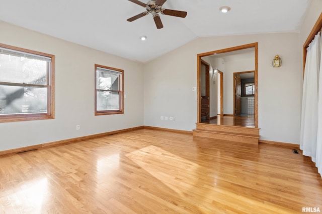 empty room with ceiling fan, plenty of natural light, lofted ceiling, and light wood-type flooring