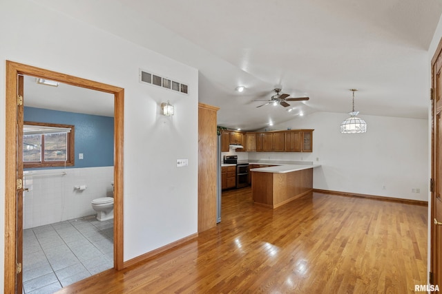 kitchen featuring pendant lighting, lofted ceiling, electric range, light hardwood / wood-style floors, and kitchen peninsula