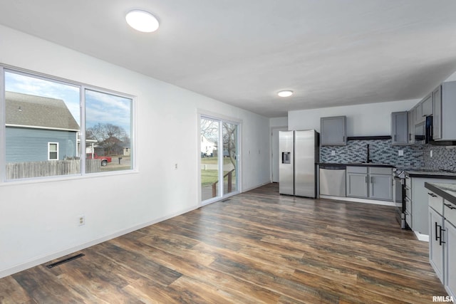 kitchen featuring gray cabinetry, sink, stainless steel appliances, dark hardwood / wood-style flooring, and backsplash