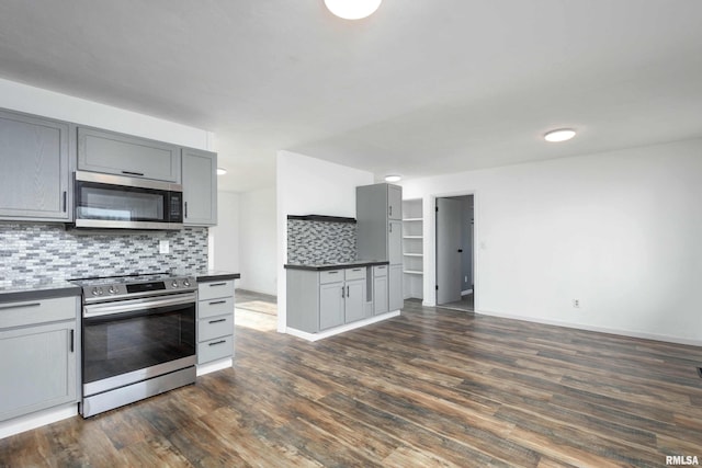 kitchen with decorative backsplash, gray cabinets, dark hardwood / wood-style floors, and stainless steel appliances