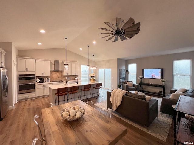 dining room with lofted ceiling, light wood-type flooring, ceiling fan, and sink