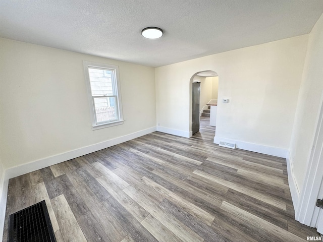 empty room with hardwood / wood-style floors and a textured ceiling