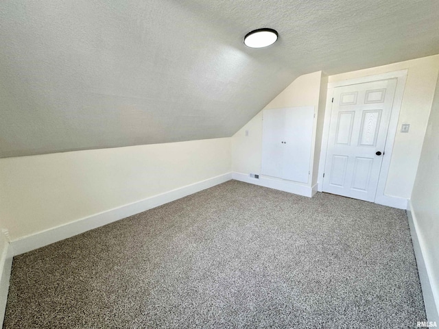 additional living space featuring carpet flooring, a textured ceiling, and vaulted ceiling