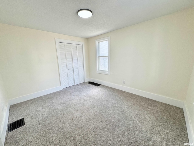 unfurnished bedroom with carpet flooring, a closet, and a textured ceiling