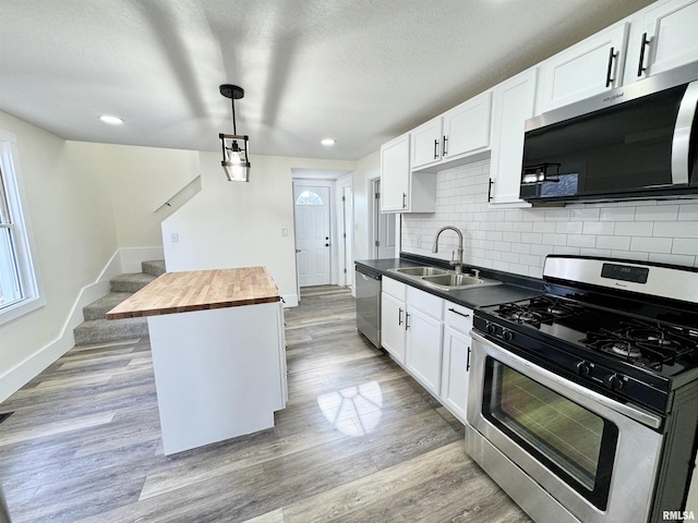 kitchen with wooden counters, decorative light fixtures, light hardwood / wood-style floors, white cabinetry, and stainless steel appliances