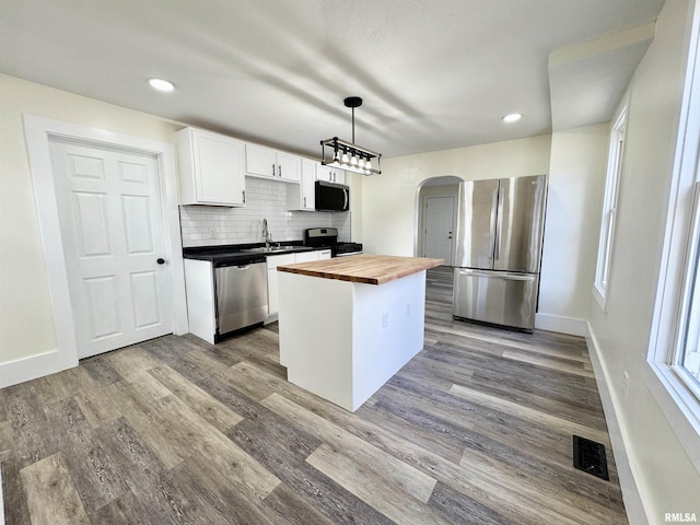 kitchen with white cabinetry, a center island, hanging light fixtures, wooden counters, and appliances with stainless steel finishes