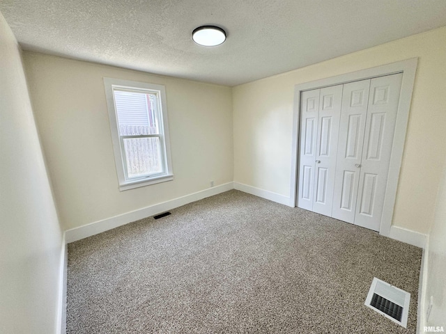 unfurnished bedroom with a textured ceiling, carpet floors, and a closet