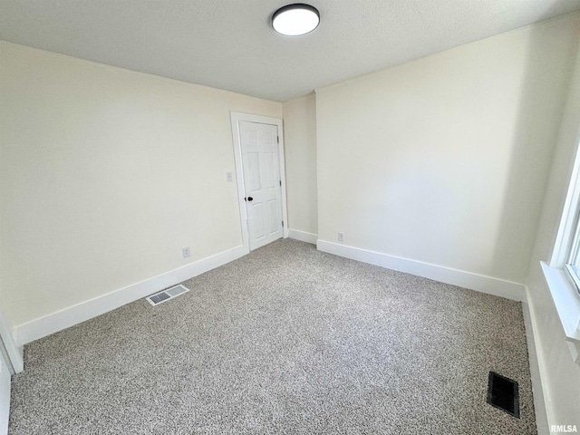 carpeted empty room featuring a textured ceiling