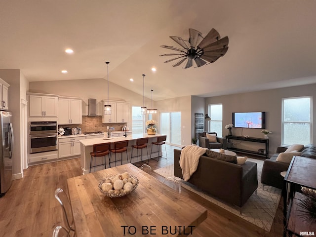 dining space featuring sink, vaulted ceiling, ceiling fan, and light hardwood / wood-style floors