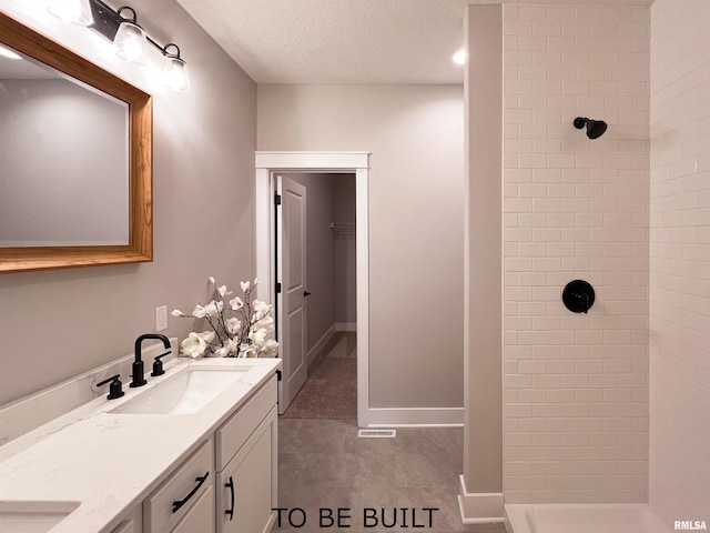 bathroom featuring a textured ceiling, a tile shower, and vanity