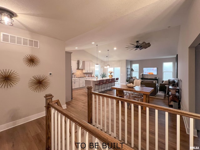 interior space with a healthy amount of sunlight, hardwood / wood-style floors, vaulted ceiling, and a textured ceiling