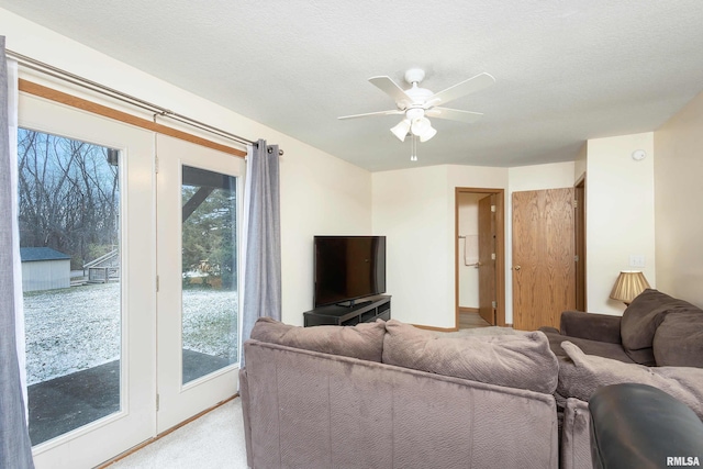 living room with a textured ceiling, ceiling fan, and light carpet