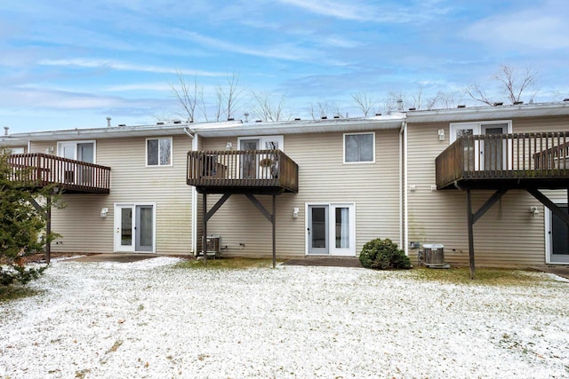 snow covered back of property featuring a deck and central air condition unit