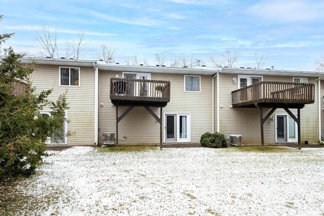 snow covered rear of property featuring a balcony and central air condition unit