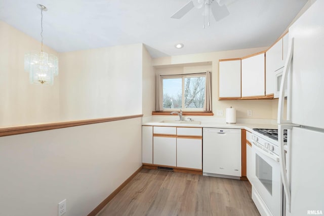 kitchen featuring white appliances, sink, light wood-type flooring, decorative light fixtures, and white cabinetry