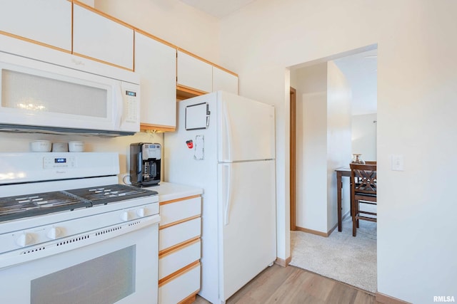 kitchen with white cabinets, light hardwood / wood-style floors, and white appliances