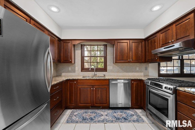 kitchen featuring light stone countertops, stainless steel appliances, light tile patterned flooring, and sink