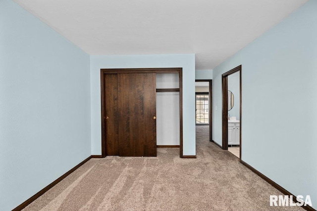 unfurnished bedroom featuring light carpet and a closet