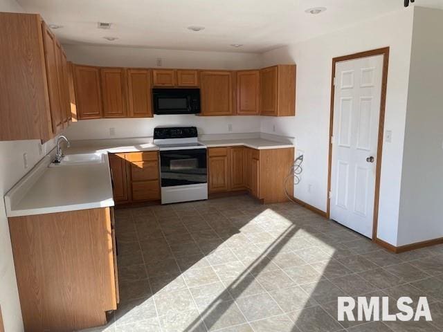 kitchen with black microwave, a sink, baseboards, light countertops, and electric range oven