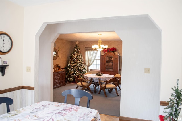 carpeted dining room featuring a notable chandelier