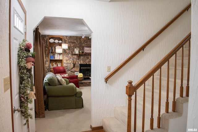 staircase with carpet flooring and a fireplace