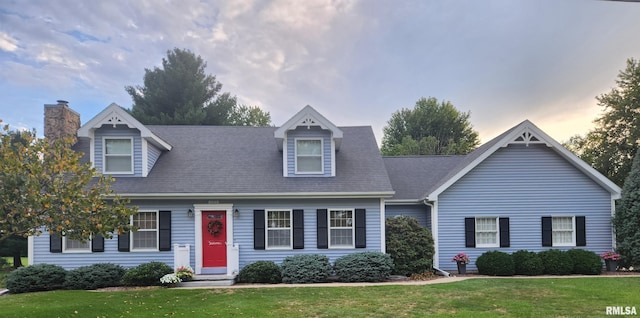 cape cod-style house with a lawn