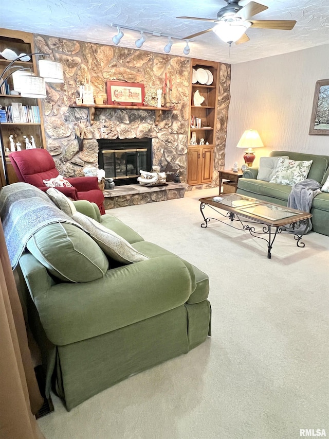 carpeted living room with rail lighting, a textured ceiling, ceiling fan, built in features, and a fireplace