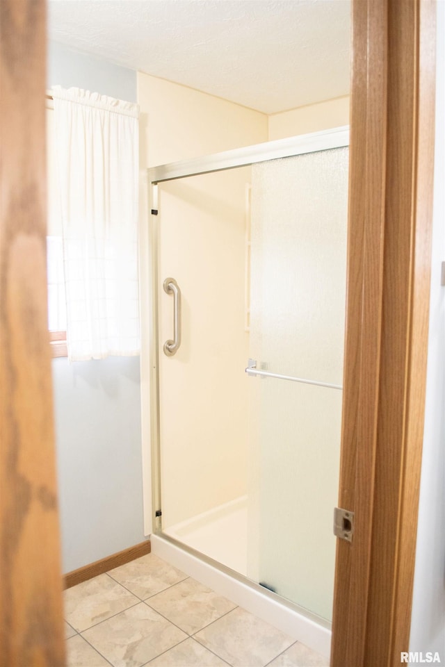 bathroom with tile patterned flooring and a shower with shower door