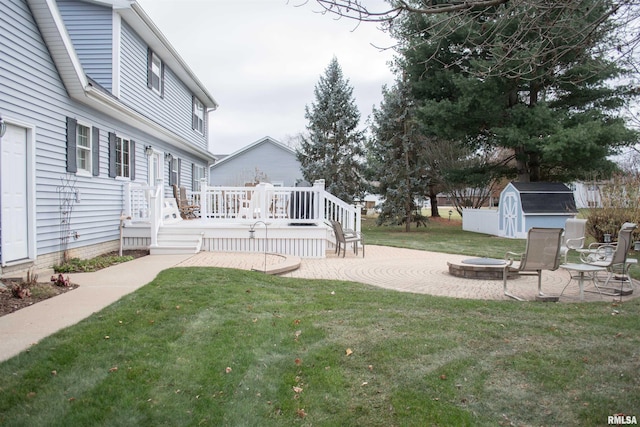 view of yard featuring a storage shed, a patio, a fire pit, and a deck