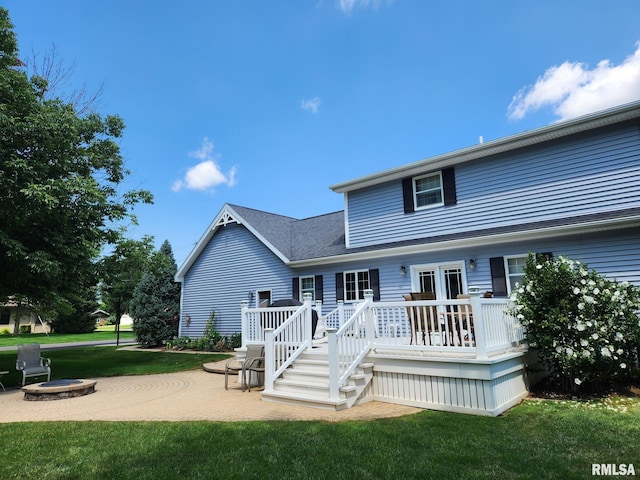 rear view of property featuring a yard, a fire pit, a deck, and a patio area