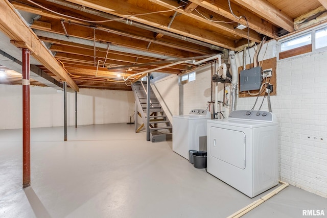 basement with washer and dryer, electric panel, and brick wall