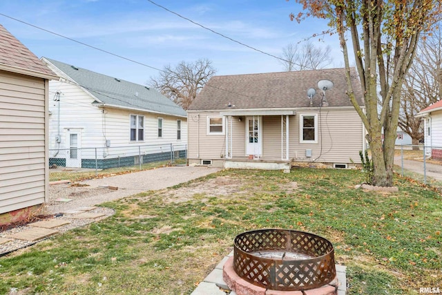 back of property featuring a lawn and an outdoor fire pit